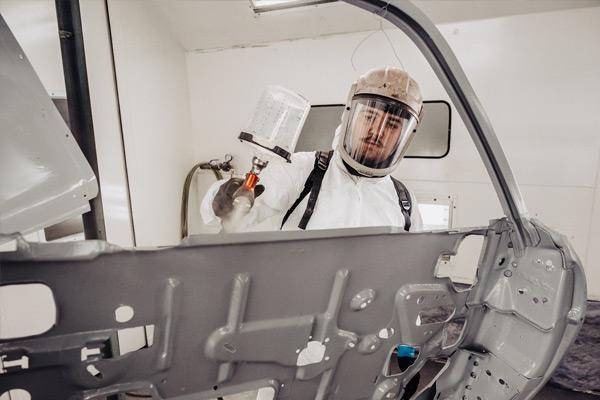 A student painting the exterior of a car 