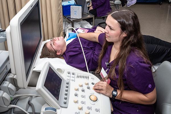 Sonography student using an ultra sound machine on a patient's shoulder