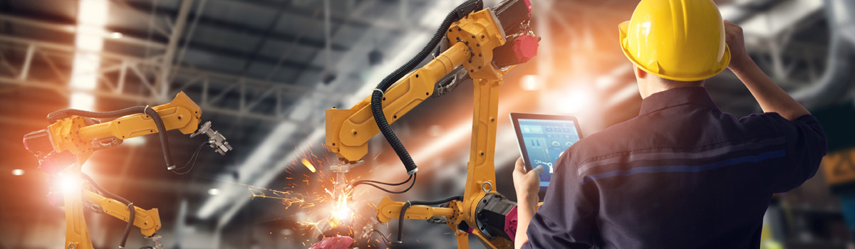 Worker testing industrial machinery and robotics assembly system