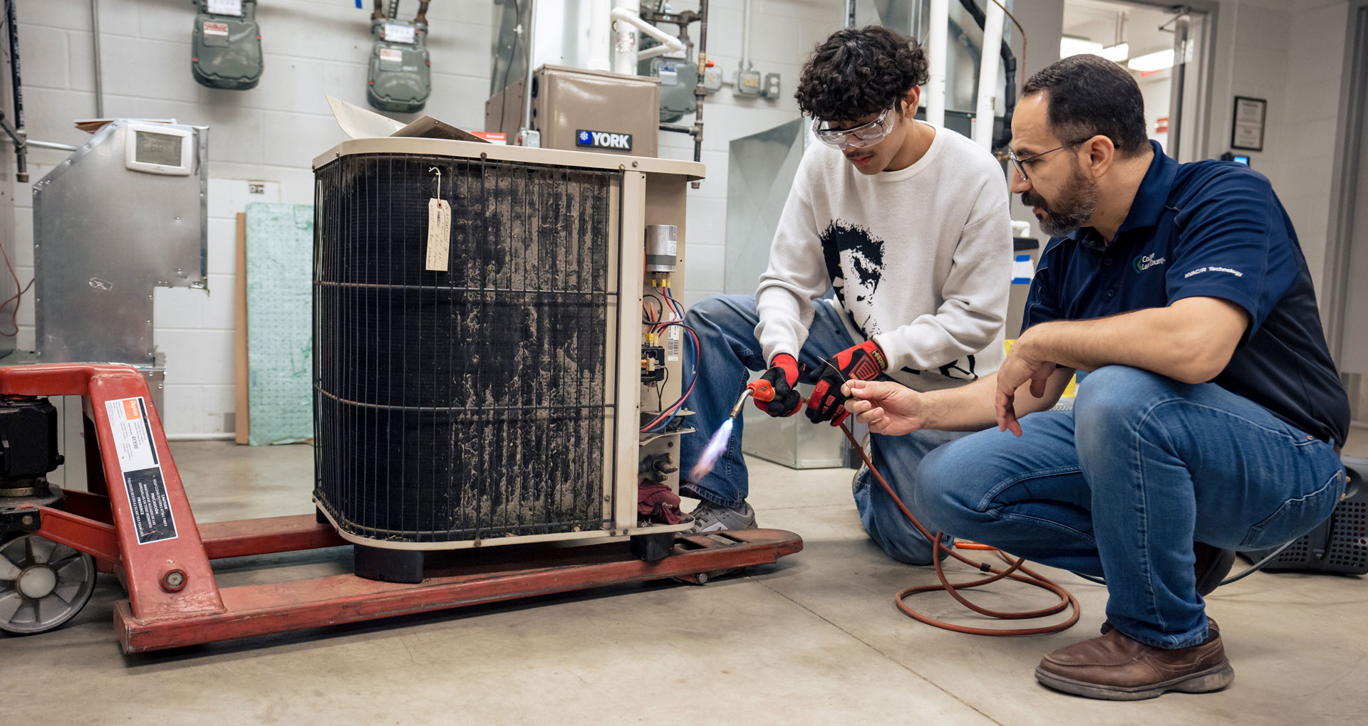 Student and instructor working on air conditioning unit