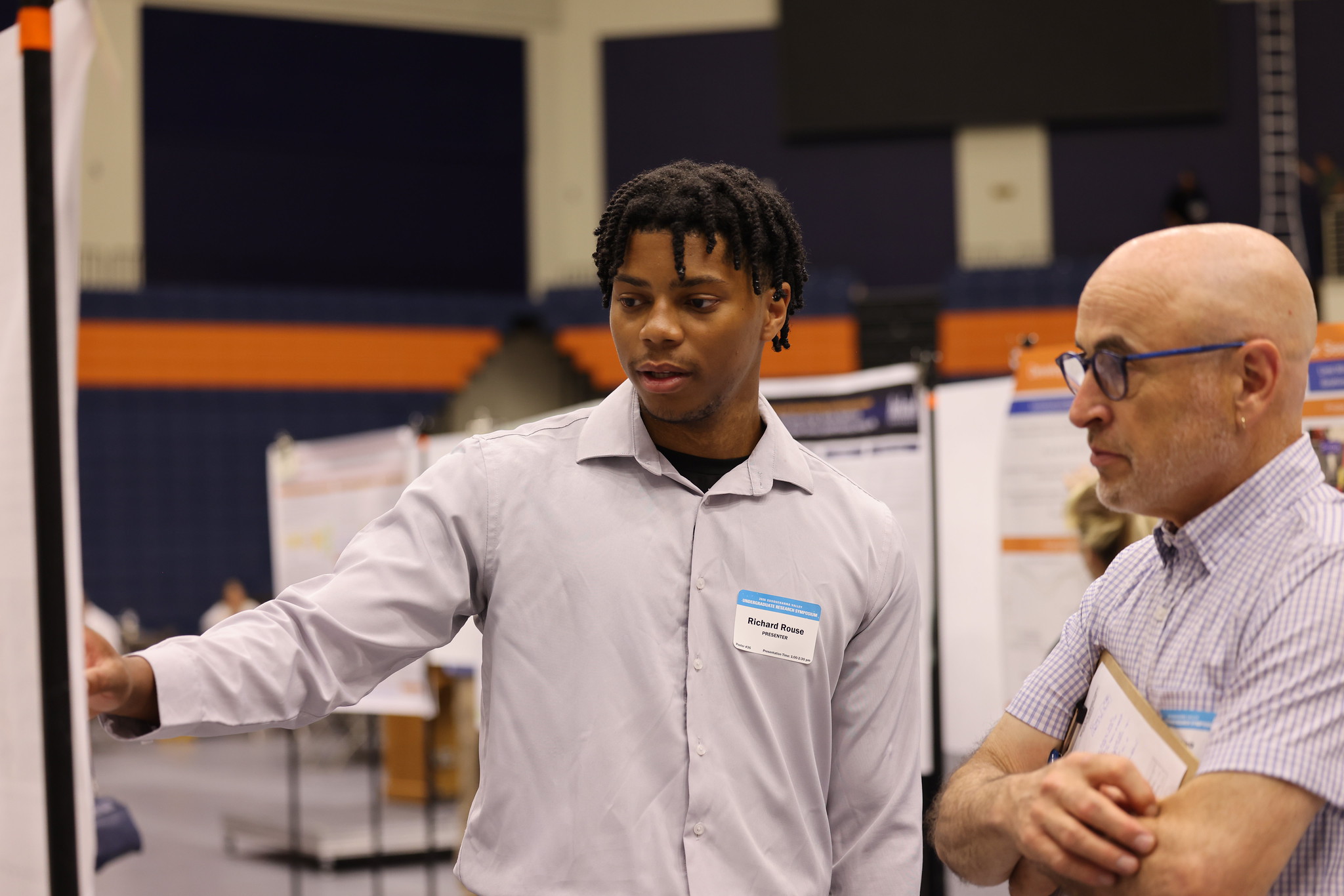 A student explains research project poster to a judge.