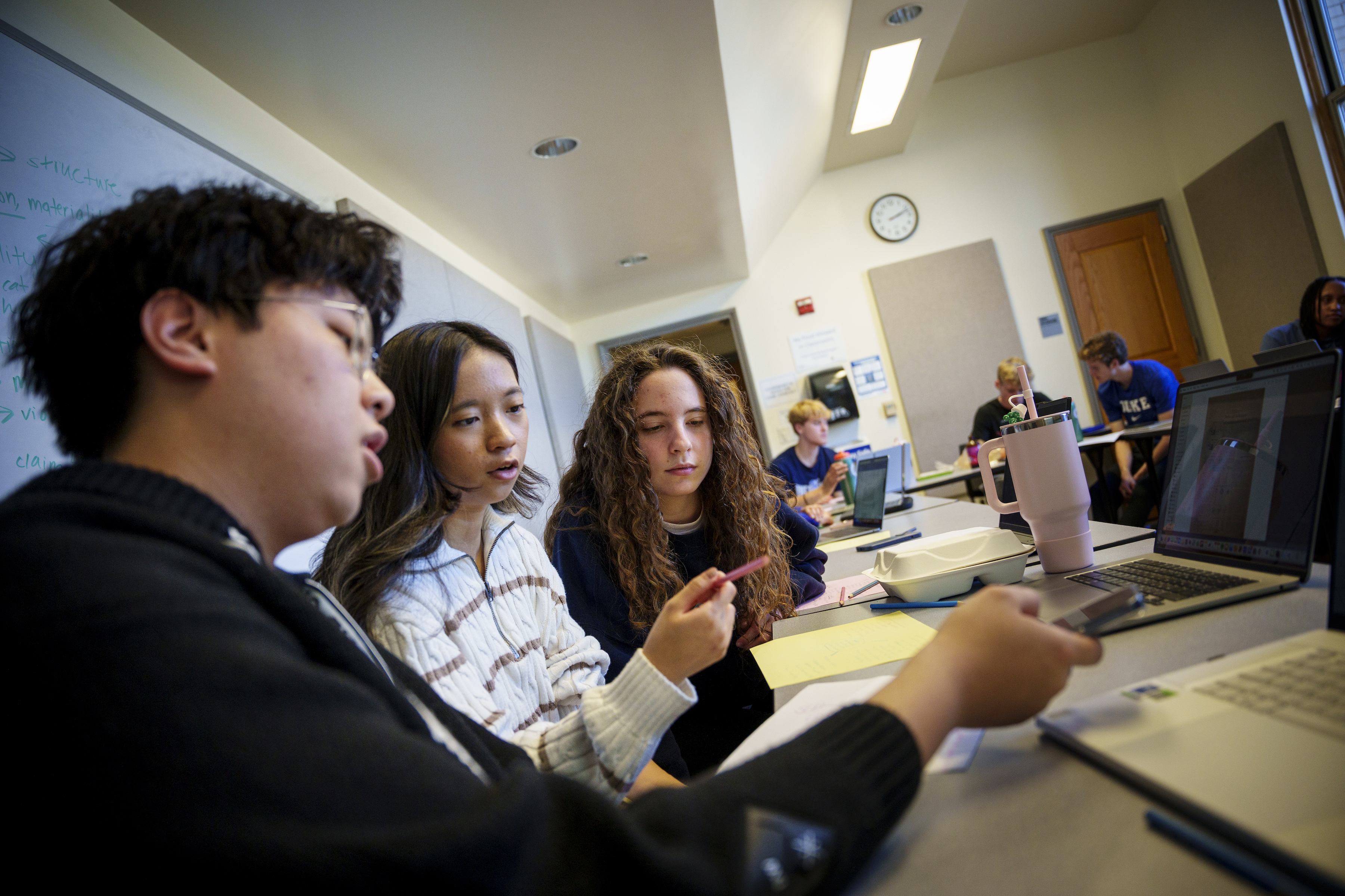 A classroom of students in a Thompson Writing Program course with three students working together at a laptop.