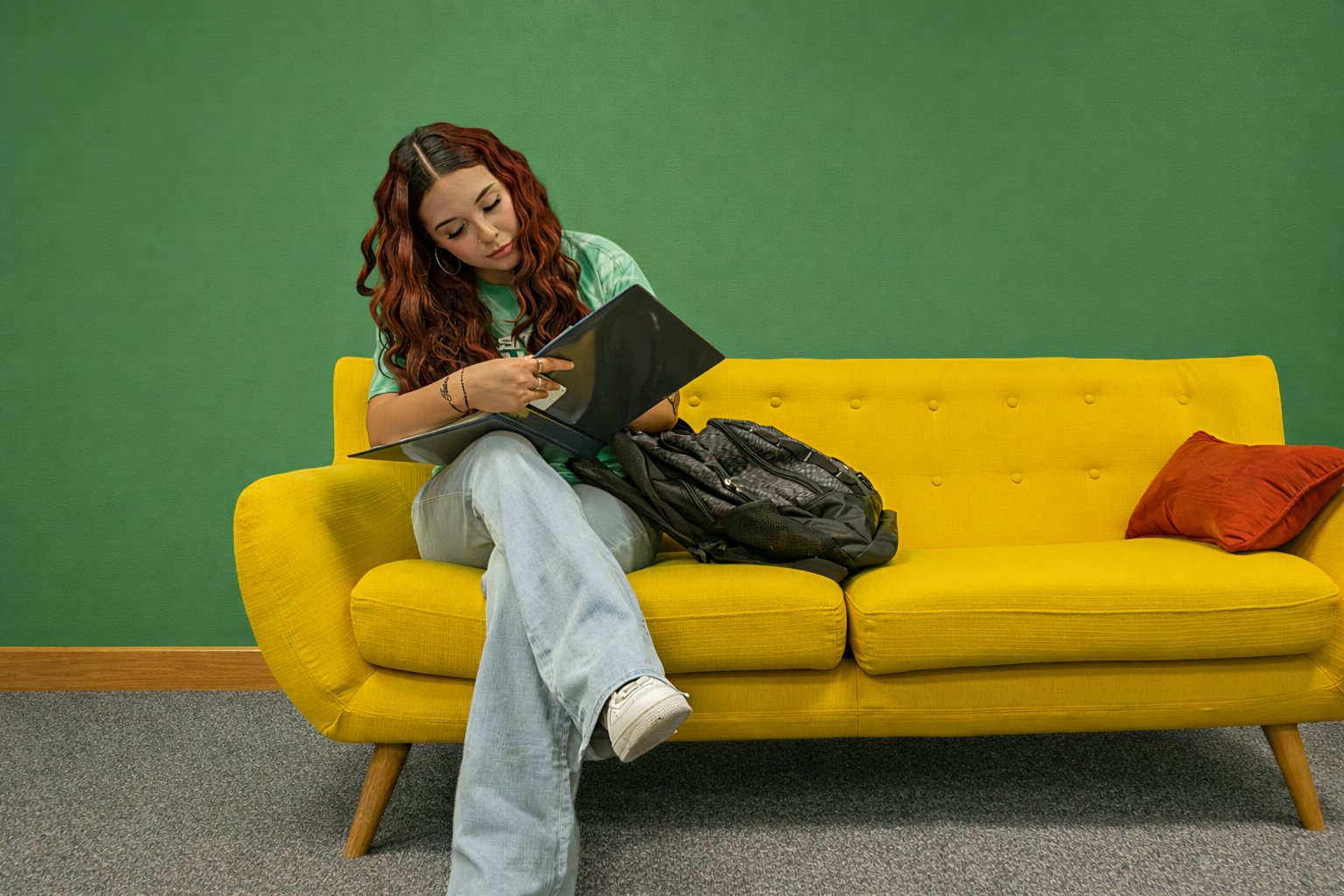 A female student writing notes while sitting on a yellow sofa