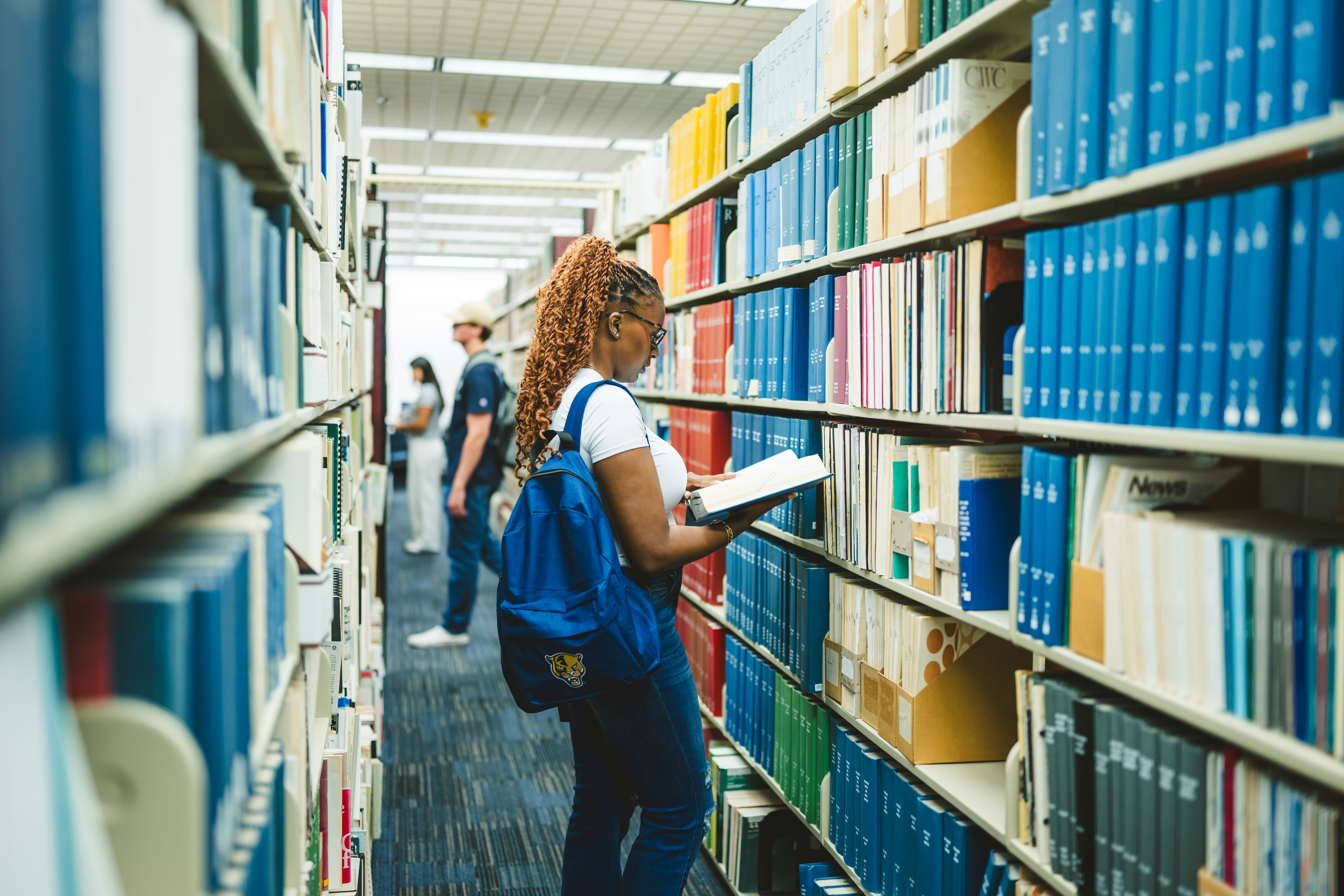 Student reading a book in aisle of Steven and Dorthea Green Library