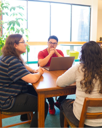 Three professionals sitting around a table discussing business.