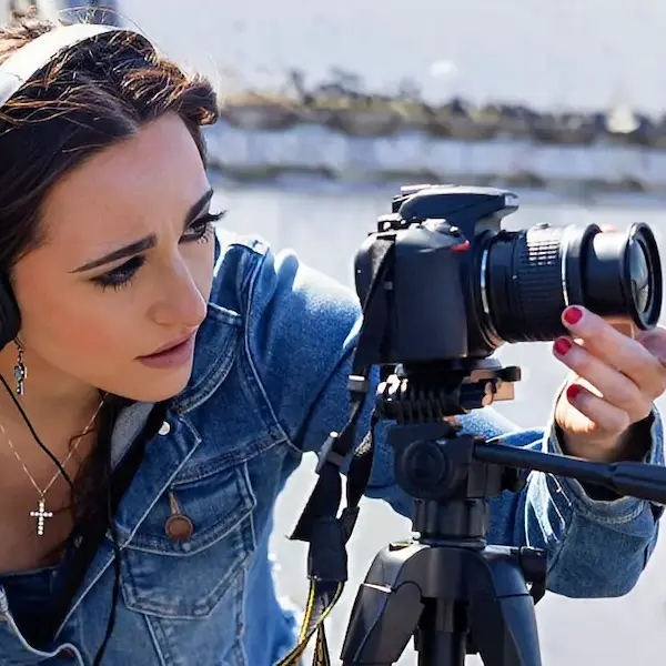 A student adjusts a tripod-mounted camera during a Visual Art Program shoot at Stockton University. | Program page | arts-humanities | communication-studies.html