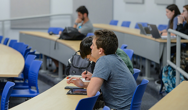 student listening to a professor in a classroom with other students