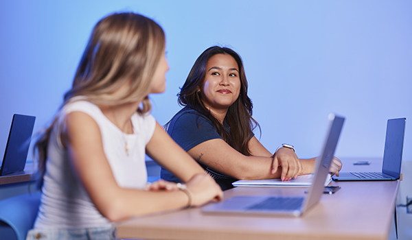 student looking at her friend while they sit in a classroom